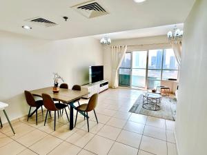 een woonkamer met een tafel en stoelen en een televisie bij Luxury Apartment Al Khan Corniche View 2 BD in Sharjah