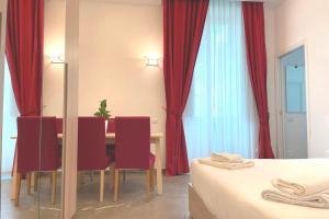 ein Esszimmer mit roten Vorhängen sowie einem Tisch und Stühlen in der Unterkunft Manfredi House San Pietro in Rom