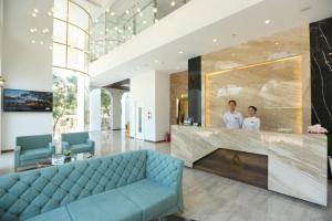 two men standing in a lobby with a blue couch at RHM Luxury Hotel And Suite in Da Nang