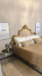 ein Bett mit einem goldenen Rahmen und einem Tisch in der Unterkunft Guest House Mameli44 in Busto Arsizio