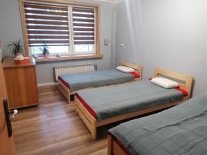 Cette chambre comprend 3 lits et une fenêtre. dans l'établissement Apartament przy puszczy, à Hajnówka