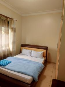 a bed sitting in a room with a window at Twinkle Blue Inn in Namugongo