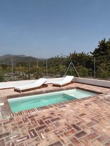 uma piscina com duas espreguiçadeiras em Cortijo Cantalobos em Almuñécar