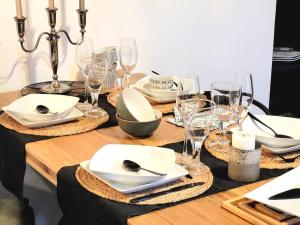 uma mesa de madeira com pratos brancos e copos de vinho em Gîte La Fontaine des Prés em Cherbourg en Cotentin