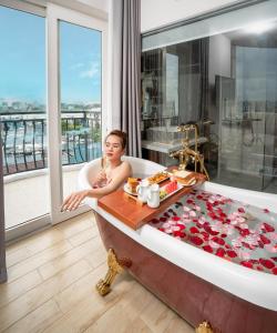 una donna in una vasca da bagno in una stanza con vista di RHM Luxury Hotel And Suite a Da Nang
