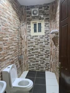 a bathroom with a toilet and a stone wall at Dshale Apartments in Taif