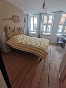 a bed in a room with wooden floors and windows at La chambre de pousse in Boulogne-sur-Mer