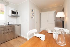 a kitchen with a wooden table and chairs and a kitchen with a microwave at Haus Delft Jakea in Juist +8 photos