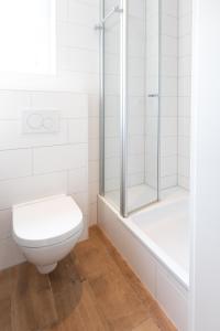 a white bathroom with a toilet and a shower at Haus Delft Jakea in Juist