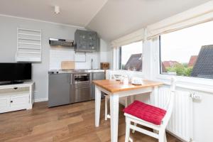 a kitchen with a table with a red seat at Haus Delft Baoule in Juist