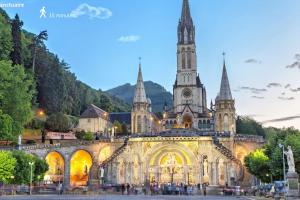 an old building with a clock tower and a church at Foucault - Appartements - au cœur de Lourdes in Lourdes