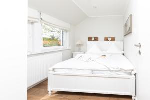 a white bed in a white bedroom with a window at Haus Delft Baoule in Juist
