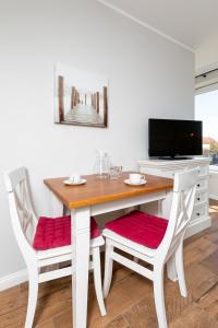 a dining room table with two chairs and a television at Haus Delft Elisa in Juist