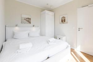 a white bedroom with a large white bed with white pillows at Haus Delft Elisa in Juist