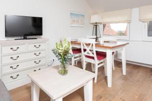 a living room with a table and a tv at Haus Delft Jaap Jacoba in Juist