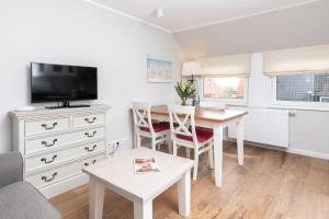 a living room with a table and a tv at Haus Delft Jaap Jacoba in Juist