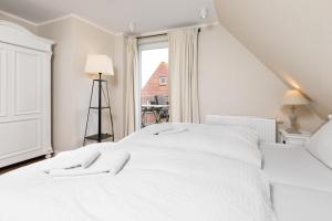 a white bed in a room with a window at Haus Delft Jaap Jacoba in Juist
