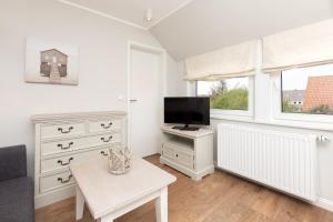 a living room with a tv and a couch at Haus Delft Angelino in Juist