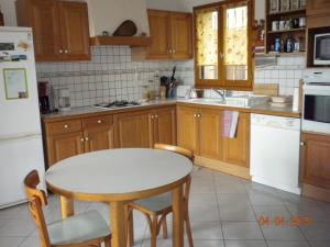 a kitchen with a table and a white refrigerator at Maison de Vacances de Récailleau in Nérac