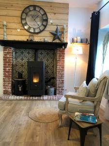 a living room with a fireplace with a clock at Gîte La Fontaine des Prés in Cherbourg en Cotentin