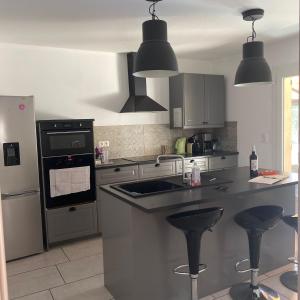 a kitchen with a sink and two bar stools at VILLA très bien équipée pour les vacances in Boisset-et-Gaujac