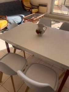 een witte tafel met een stoel en een vaas erop bij Beau T3 face Rouet plage avec garage in Carry-le-Rouet
