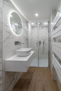 een witte badkamer met een wastafel en een douche bij Déja Blue Old City Center studio. in Sofia