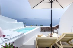 a white house with a plunge pool and chairs and an umbrella at Cleo's Dream Villa in Oia