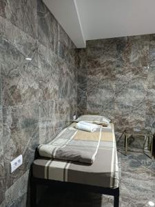 ein Schlafzimmer mit einem Bett und einer Steinmauer in der Unterkunft Berić Rooms Hostel in Šabac
