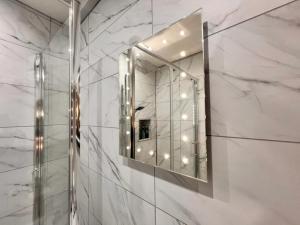 a bathroom with a mirror on a marble wall at Cosy & Convenient space near M1, EM Airport & City in Nottingham