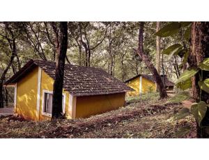 una pequeña casa amarilla en medio de un bosque en The Earthen Nest Resort, Canacona, Goa en Poinguinim