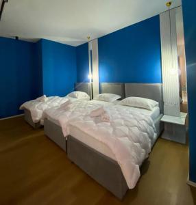 a blue bedroom with two beds with white sheets at Capital Suites Center in Tirana