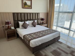 a bedroom with a large bed and a large window at PRIMOTEL Suites As Salamah in Jeddah