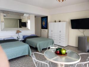 Hotel Torres Gemelas vista al mar a pie de playa في أكابولكو: غرفة بسريرين وطاولة عليها فاكهة
