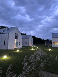 una casa blanca con luces en un patio por la noche en Morze2 - domy całoroczne nad morzem, en Lubiatowo
