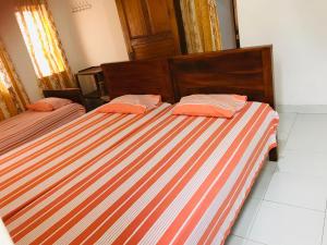 2 camas con almohadas naranjas juntas en BATTI REST, en Batticaloa