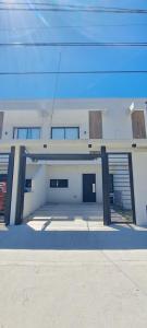 a white building with a garage with a door at Berasain Apartment - Tu hogar cerca del Aeropuerto de Ezeiza in Monte Grande