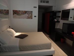 Schlafzimmer mit einem weißen Bett und einem TV in der Unterkunft Blue Shades ApartHotel in Pisa
