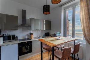eine Küche mit einem Tisch und Stühlen sowie einem Fenster in der Unterkunft Appartement Saint-Malo - 10 mètres de la mer in Saint-Malo