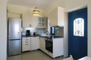 a kitchen with white appliances and a blue door at Fanaraki Villas - West in Moúdhros