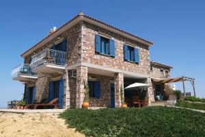 a stone house with blue shutters on a beach at Fanaraki Villas - West in Moúdhros
