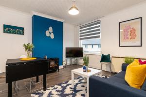 a living room with a blue wall and a piano at Modern Apartment in Wigston with Free Parking! in Wigston Magna