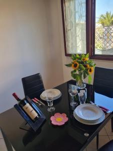 Una mesa negra con platos y un jarrón de flores. en Casa Azzurra en San Sperate