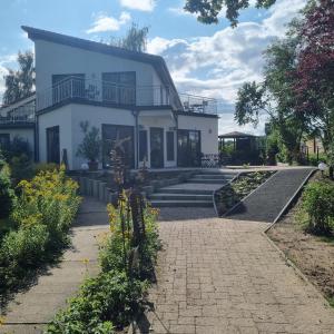 una casa blanca con una pasarela delante de ella en Waldhof Golf-Fewo, en Korswandt