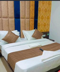 a large bed with white sheets and brown pillows at Hotel Rudrax - Anand in Anand