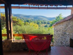 a red chair sitting on a porch with a view at La Bergerie en Cévennes in Mialet
