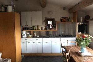 a kitchen with white cabinets and a wooden table at La Bergerie en Cévennes in Mialet