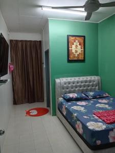 a bedroom with a bed and a green wall at RizqFateh Homestay in Kluang