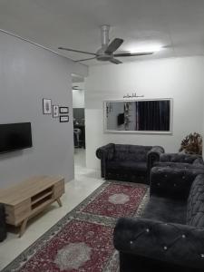 a living room with black furniture and a flat screen tv at RizqFateh Homestay in Kluang
