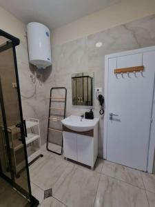 a white bathroom with a sink and a mirror at Central Gem Tirana in Tirana